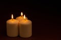 Three whiteÃÂ candlesÃÂ flameÃÂ burningÃÂ onÃÂ dark backgroundÃÂ withÃÂ copyÃÂ space forÃÂ text Royalty Free Stock Photo